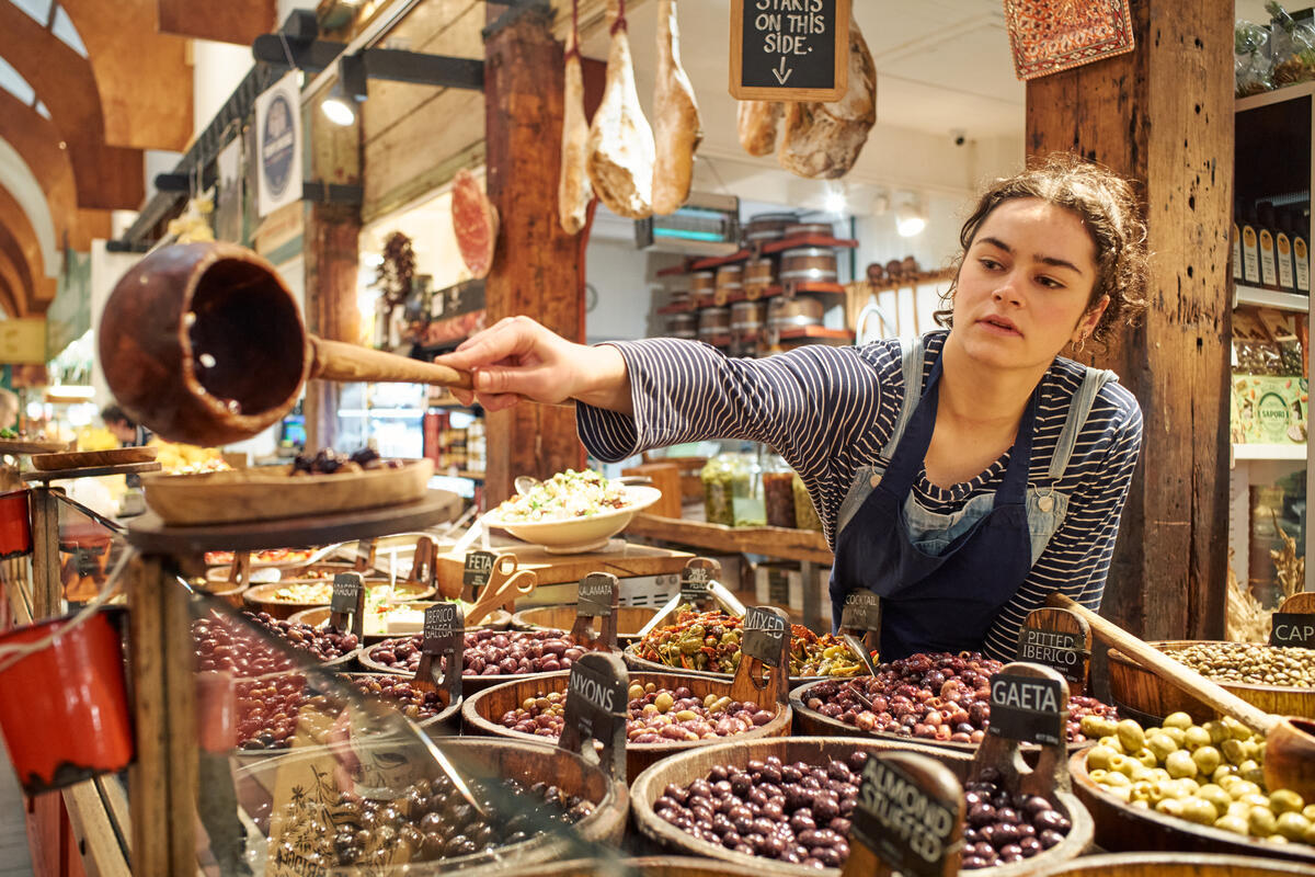 A young worker serving customers at a food stall in the English Market, Cork City